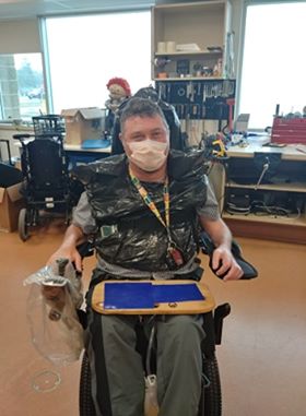 M. Woodworth portantt un masque et assis dans son fauteuil roulant motorisé 