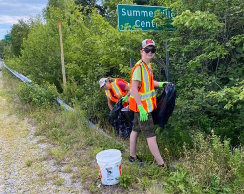 Pair of volunteers pulling garbage from the bush.