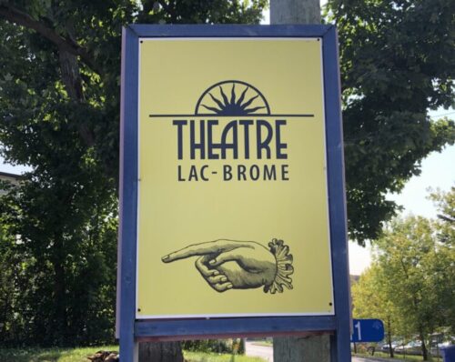 A photo of the yellow and blue Theatre Lac Brome parking lot sign.