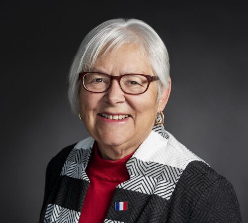 Louise Imbeault souriante portant une épingle du drapeau acadien