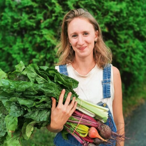 Claire May en salopette tenant des légumes