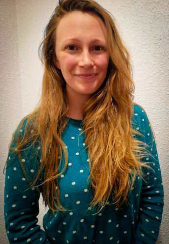 Élizabeth Vickers-Drennan, habillée en pull vert, souriante devant un fond uni.