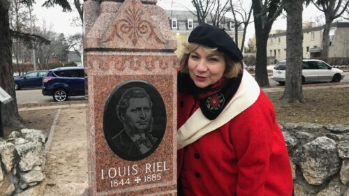 Paulette Duguay debout à côté de la pierre tombale de Louis Riel.