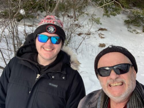 Gérard Picot et son fils à l'extérieur en hiver, chacun avec des lunettes de soleil et une tuque