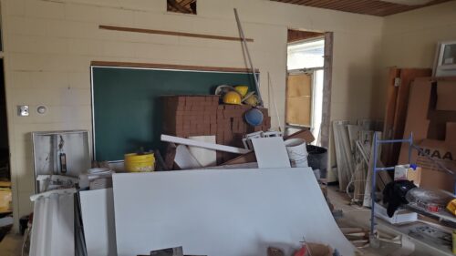 A classroom is undergoing renovations with bricks and construction supplies piled up.