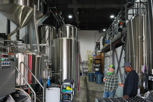 Two people standing in a brewery.