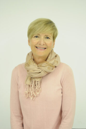 Linda Parker smiling, wearing a scarf, on a white background.