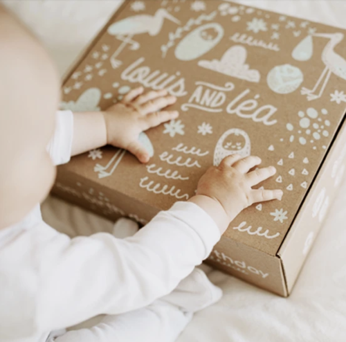 une boîte avec de l'écriture blanche de Louis and Léa et un bébé qui le tien.
