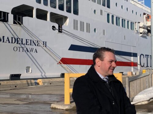 Emmanuel Aucoin stands in front of the new ferry the Madeleine II in dock on a sunny day