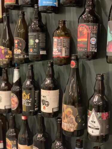Une quinzaine de différentes bouteilles de bière alligné sur un mur