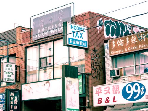 A group of shop signs in Toronto's Chinatown against a white sky background