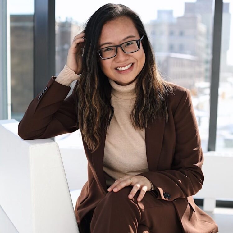 Olivia Lam sitting on a white couch in front of a window.