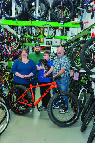 The Koops family stands inside a bike shop with bikes all around them.