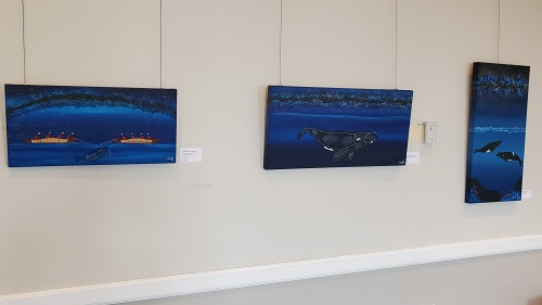 A series of blue paintings hang on a gallery wall