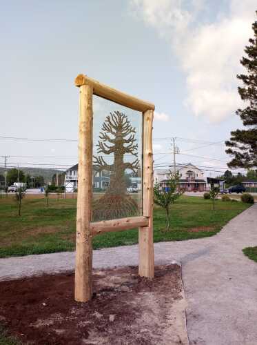 Œuvre de bois qui crée un arbre à l'extérieur dans de la terre entouré de ciment et de gazon 