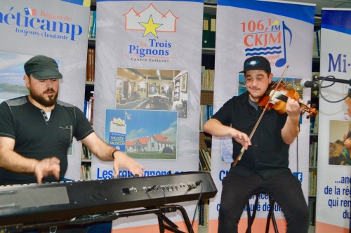 Deux hommes habillés en noir, un jouant du piano et l'autre jouant du violon.