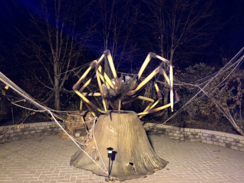 Une grosse sculpture d'une araignée jaune et noire est debout sur un tron d'arbre.