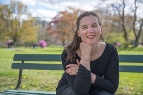 Eloise Baiet, une femme d'une trentaine d'année, sur un banc face à la caméra. elle est dans un parc.