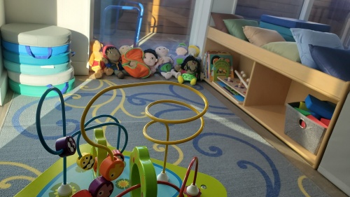 Multicoloured children's toys on a play mat with a wooden bench next to it.