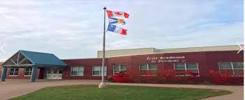 École en briques avec un mât de trois drapeaux.