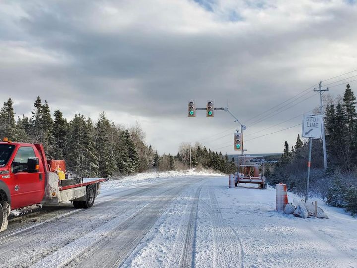 Camion rouge sur une route enneigée avec des panneaux de signalisation.