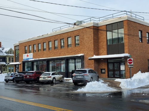 Cars parked along a street in front of a brick building on an overcast day