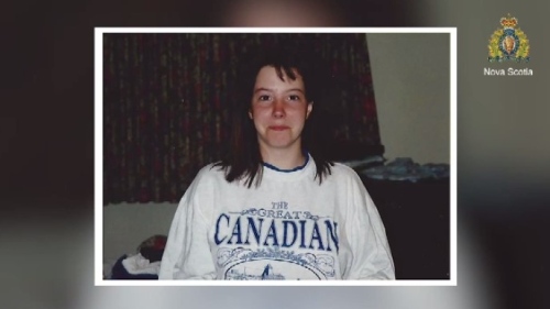 Arlene Mclean, une jeune femme brune aux cheveux ondulés portant un chandail marqué "Canadian". Elle pose dans un intérieur datant d'avant les années 2000