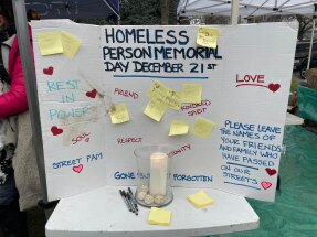 tableau blanc en carton avec des coeurs et des écrits d'hommage aux sans-abris, bougies et stylos au premier plan