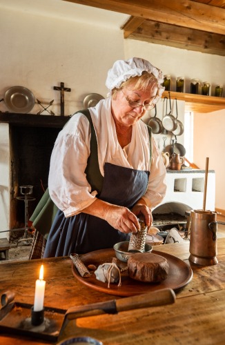 Une dame en costume authentique préparant de la nourriture dans une ancienne maison.