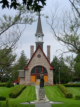 Une statue en face d'une petite église en roches par une journée d'été.