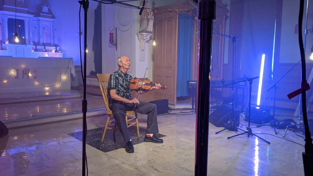 Violoneux assis sur une chaise dans une sacristie d'église.