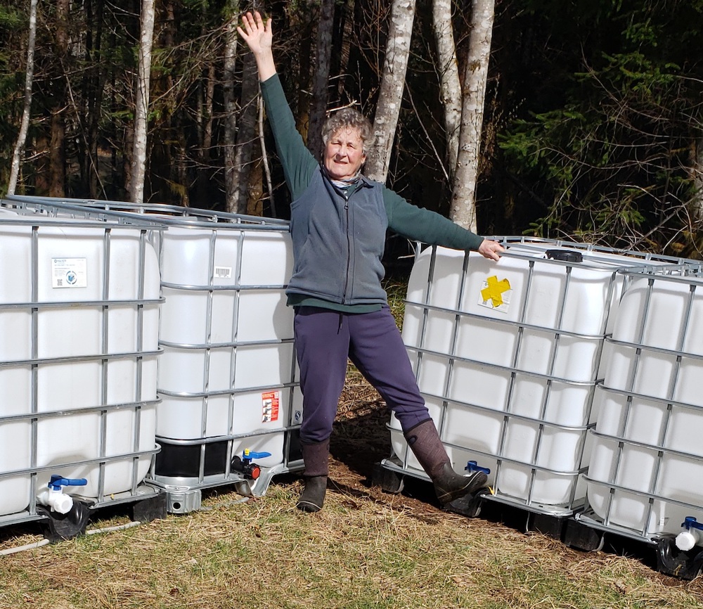 A woman strikes a pose in front of large rectangular white storage tanks.