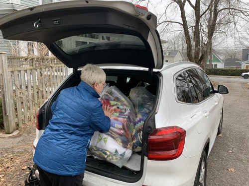 Woman loading clear bags full of blankets into vehicle