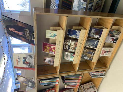 Des livres sont présentés dans une étagères en bois.