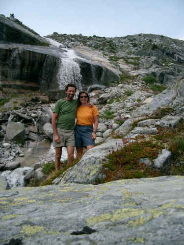 Glen and her husband are standing near a waterfall. 
