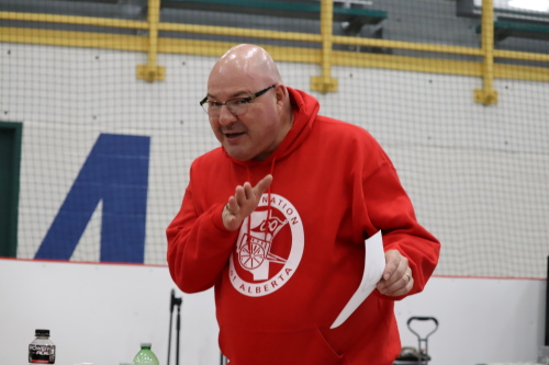 Image shows Dan Cardinal wearing a red Sweater and talking to someone at Metis Spring Music Festival