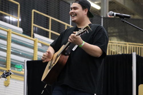 Image shows Colten Bear smiling and playing guitar