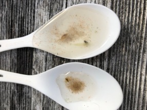 Two white plastic spoons contain murky liquid.