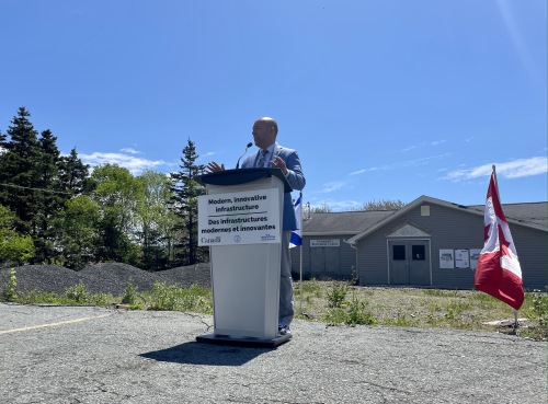 Andy Filmore is standing at the podium in front of the soon to be renovated community centre.