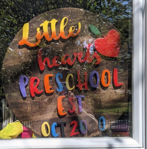 Little Hearts Preschool sign on display in a window
