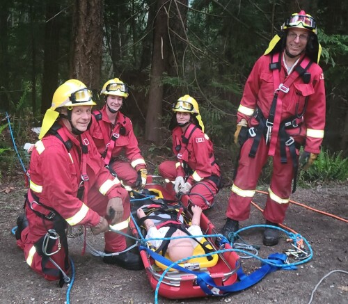 Four firefighters surround a dummy strapped to a spine board.