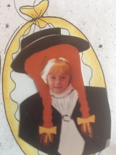 A photo of Hannah Mae Cruddas as a child, behind a Anne Shirley cutout with braids.