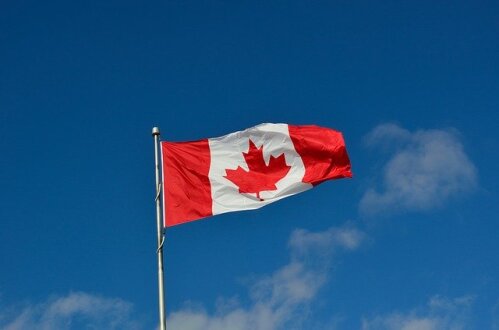 A Canadian flag flying in a blue sky.