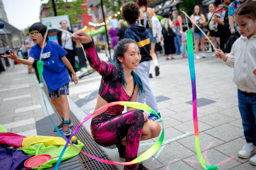 Acrobat playing with ribbons in a pink leotard, performing at the TD block party.