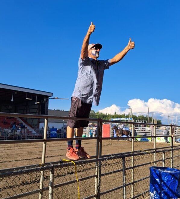 Un homme debout sur une clôture anime la foule devant lui lors d'une compétition de rodéo
