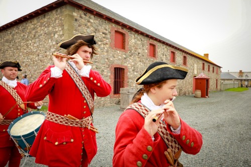 Des jeunes hommes portant des chapeaux et des habits rouges jouent de la musique dans la rue.