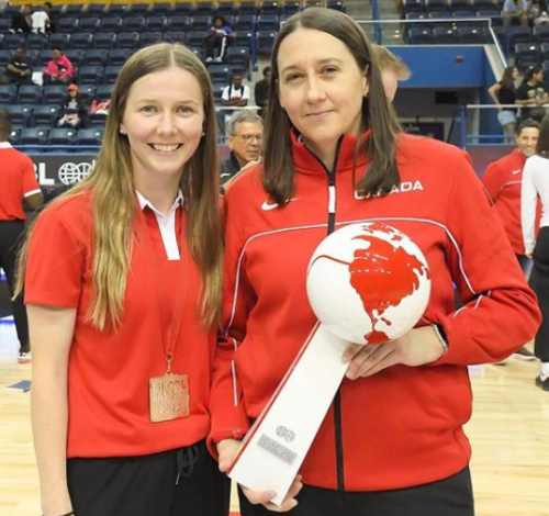 Two people in red jackets holding a white trophy.