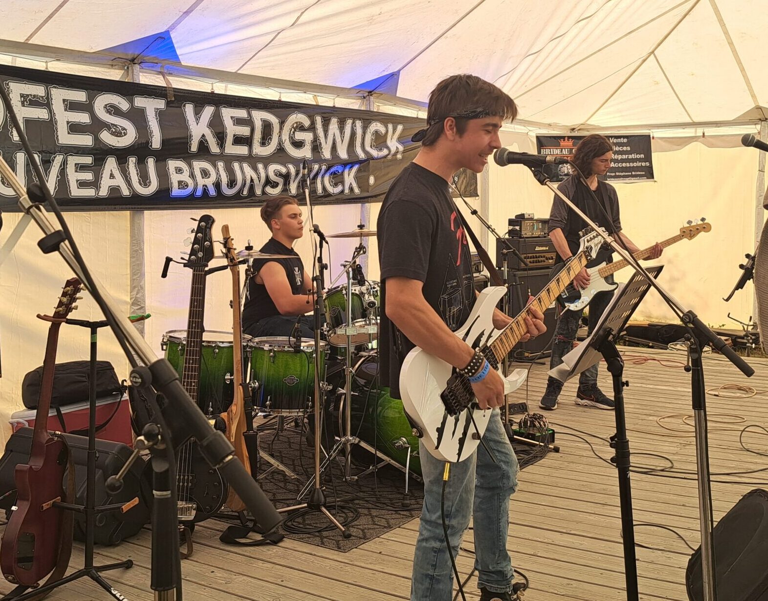 Trois en membre d'une groupe de musique rock en action durant un test de son, sur une scène