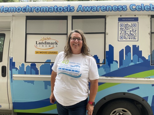 Photo of Liz Charyna smiling in front of her customized ride 'Elsie The Bus'.