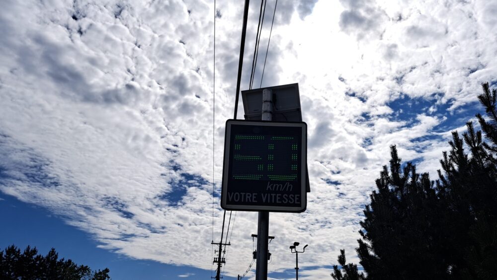 Panneau d'afficheur de vitesse en dessous de fils électriques et d'un ciel partiellement couvert